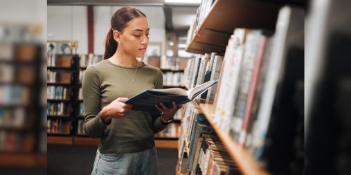 Mulher na biblioteca segurando um livro